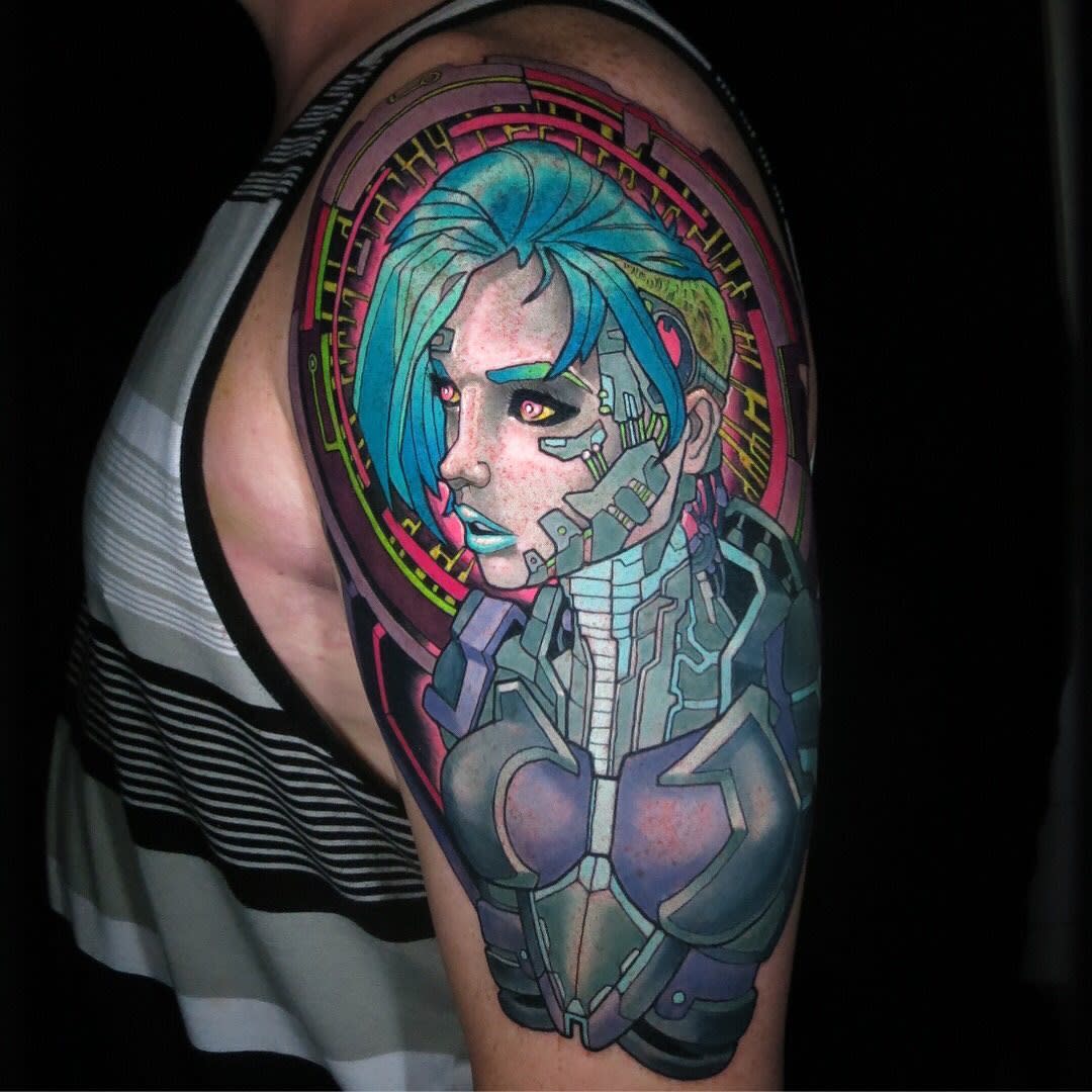 A vibrant cyberpunk tattoo of a woman with blue hair, featuring mechanical and futuristic elements